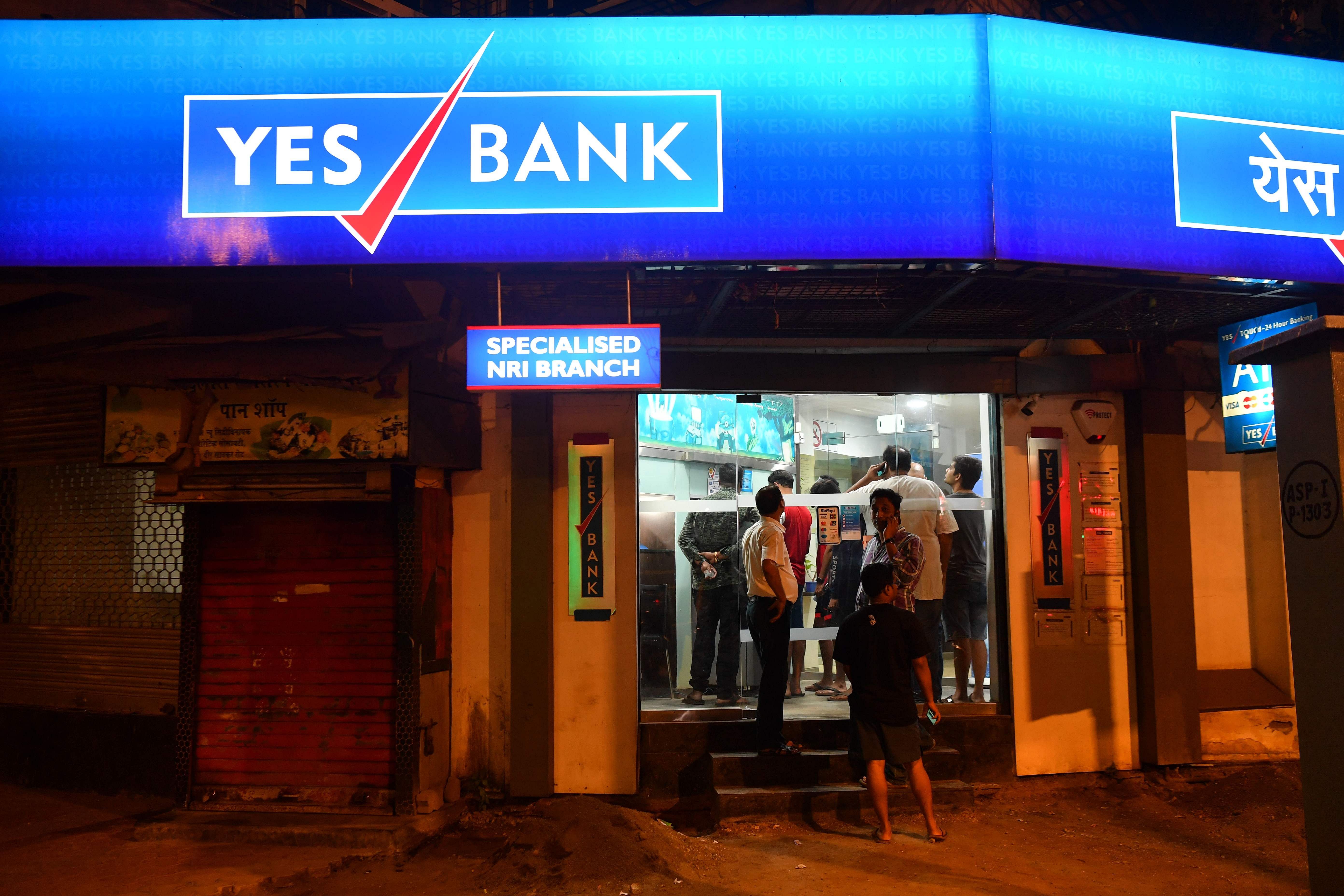 Customers of Yes Bank queue up to withdraw money from their accounts at an Automated Teller Machine (ATM) kiosk in Mumbai. (AFP Photo)