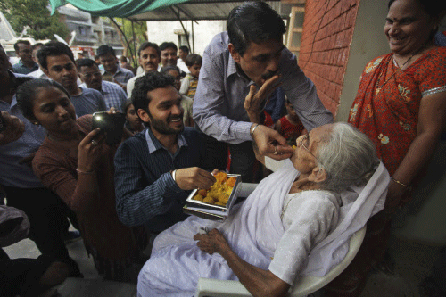 Relatives offer sweets to Hiraben, mother of Narendra Modi,as they celebrate Modi's  swearing-in ceremony. AP photo