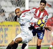 keen tussle: Sevilla's Frederic Kanoute (left) battles for possession with Sporting Gijon's Alberto Botia during their Spanish league match on Sunday.  AFP