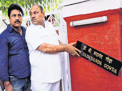 Congress ex-MLA Mukesh Sharma removes the name-plate of Railway Minister DV Sadananda Gowda during a protest demanding rollback of rail fare hike outside Railway Minister's house, in New Delhi on Tuesday. DH Photo