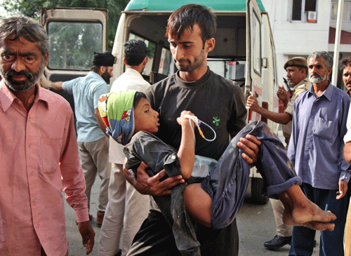 An Indian man carries a boy, injured reportedly in firing and shelling from Pakistan side at Jora farm in Ranbir Singh Pura of the India-Pakistan border, for treatment to the government medical college hospital, in Jammu, India, Wednesday, Oct. 8, 2014. Indian and Pakistani troops fired bullets and mortar shells across the border between Kashmir and Pakistan for a second day Tuesday, with both accusing the other of provoking the violence. AP Photo