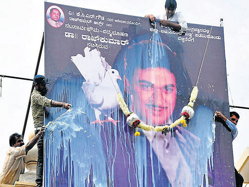Fans of Dr Rajkumar pour milk on the 30-foot-tall cutout, to celebrate the release of 'Kasturi Nivasa' in coloured version, at Woodlands theatre, in Mysore, on Friday. DH PHOTO