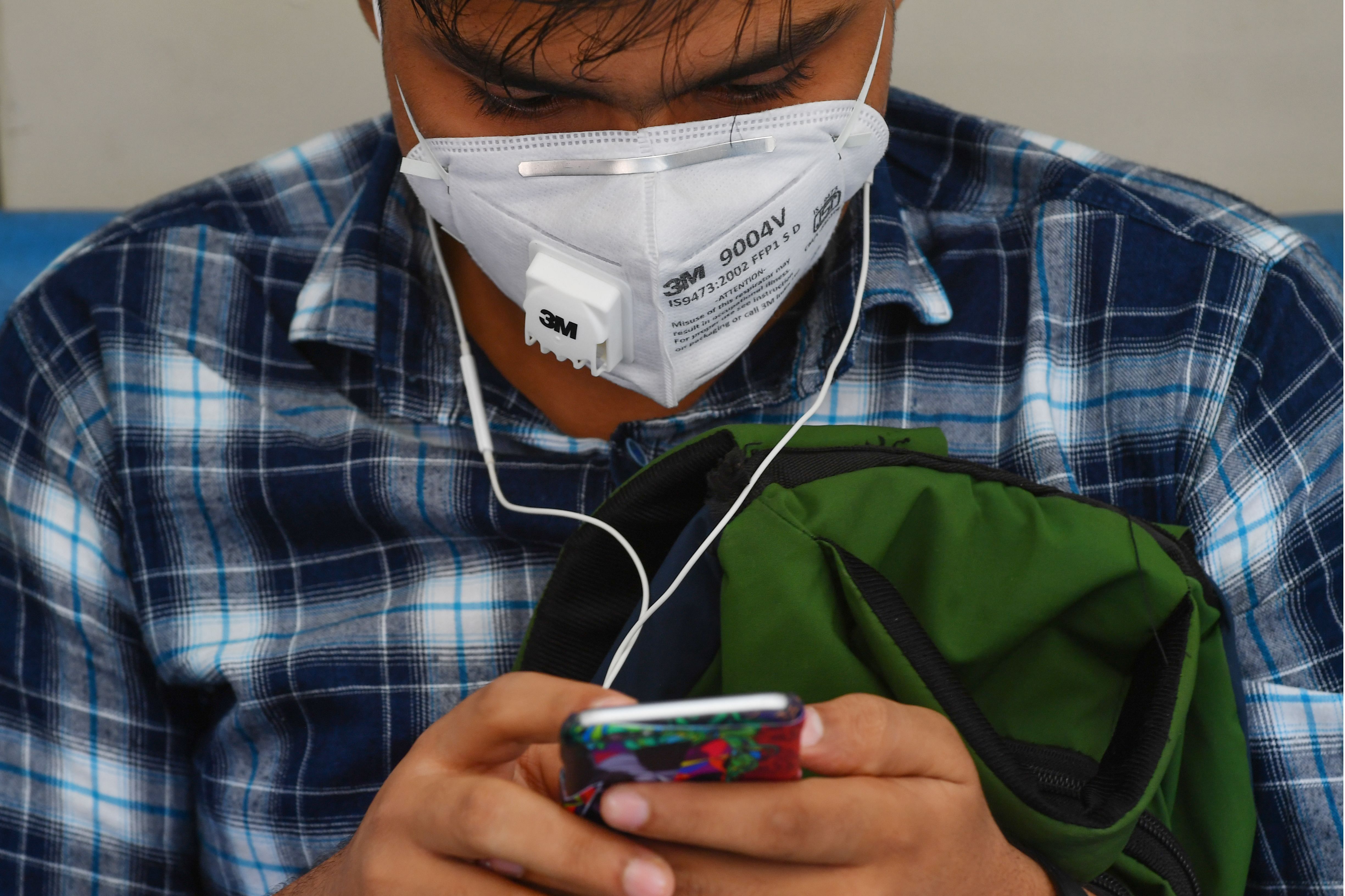 A man wearing a facemask amid concerns over the spread of the COVID-19 coronavirus uses his smart phone. (PTI)