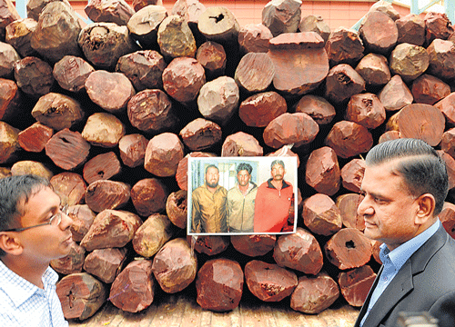 Deputy Commissioner of Police (Crime) Abhishek Goyal and Police Commissioner M&#8200;N&#8200;Reddi with logs of Red Sanders wood seized from smugglers (in photo pasted on the logs). DH photo