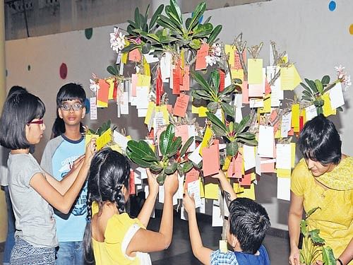 Children paper-tag their dreams onto an interactive art installation by two artists- Helena von Schoultz from Finland and Cristina Maiorescu from Romania- at the  Rangoli Metro Art Center on Sunday. DH Photo