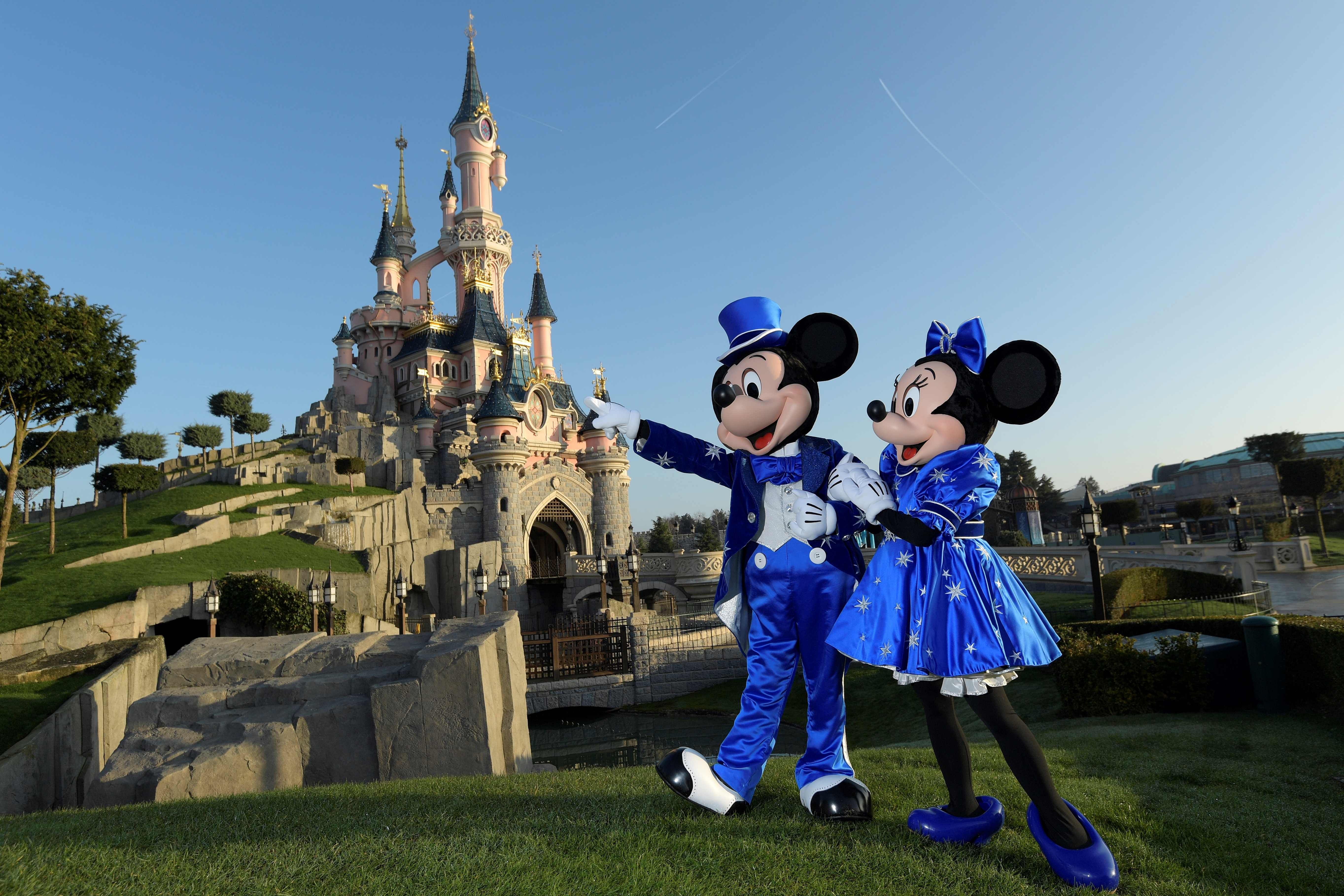  In this file photo Disney characters Mickey and Mini mouse pose on March 16, 2017 in front of the Sleeping Beauty Castle to mark the 25th anniversary of Disneyland. (Credit: AFP)