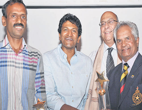 Cine star Puneeth Rajkumar (centre) felicitates former internationals Ilyas Pasha (left) and Arumainayagam on Monday. Also seen is Cyrus Confectioner (background), GM, Football Players Association of India. DH PHOTO.