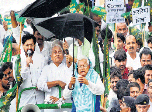 RJD chief Lalu Prasad controls his umbrella while leading a march to protest against Centre in Patna on Sunday. PTI