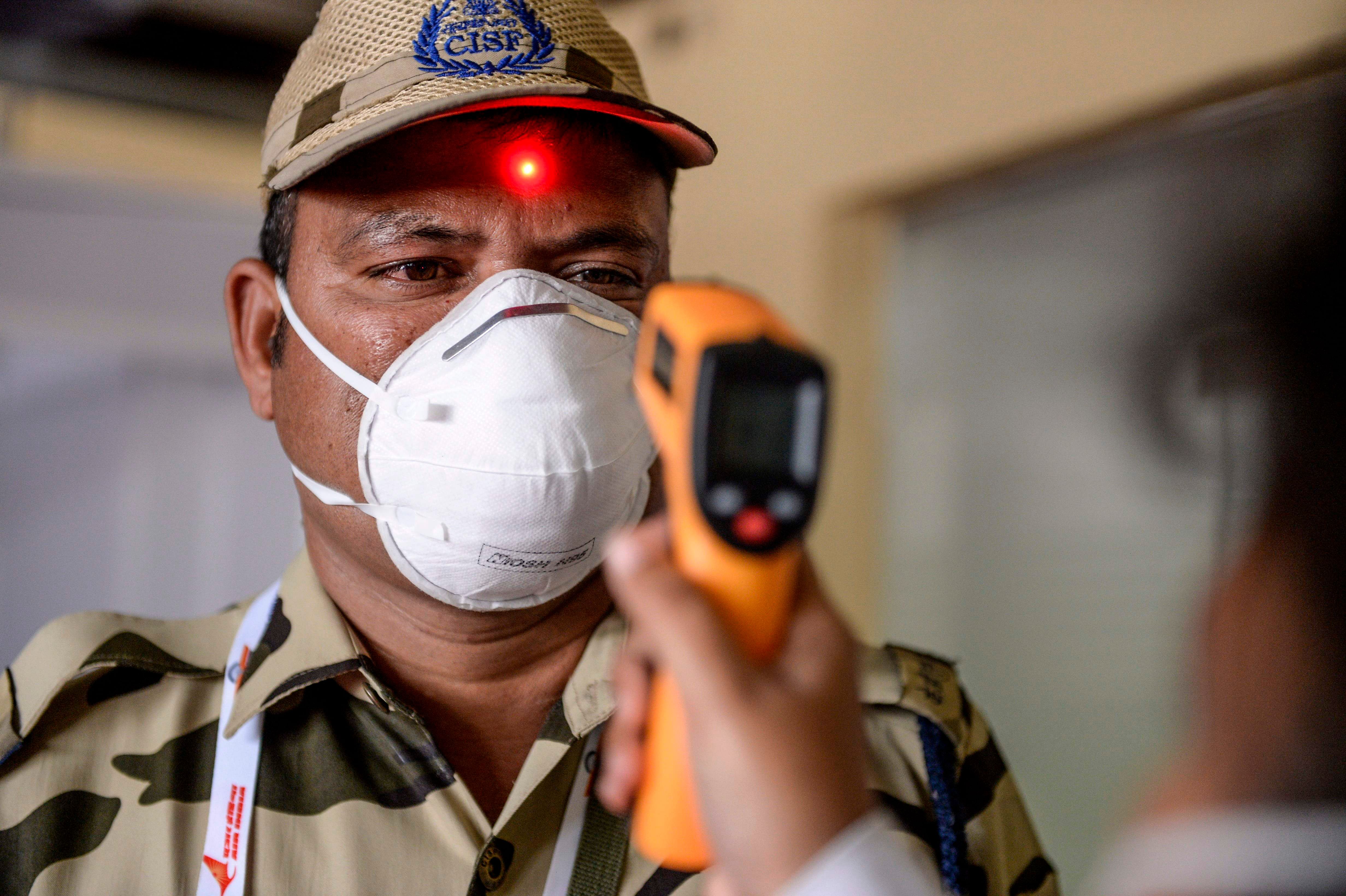 A health worker checks the temperature of a Central Industrial Security Force personnel amid concerns of the spread of the COVID-19 coronavirus. (Credit: AFP Photo)