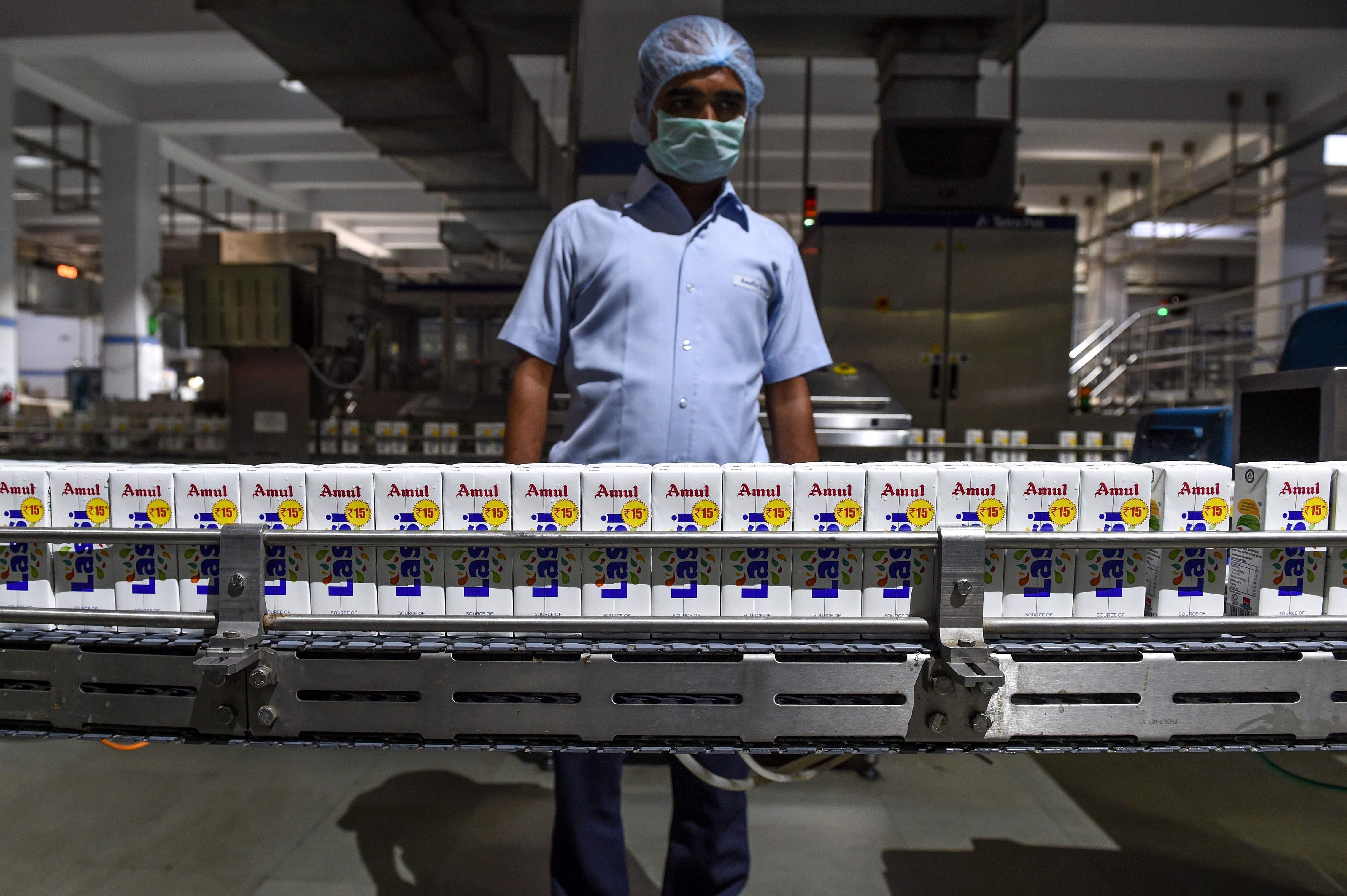 An Indian employee monitors tetra packs of lassi going through the production line at the Mother Dairy factory, which manufactures the Amul brand of ice cream, buttermilk. (AFP Photo)