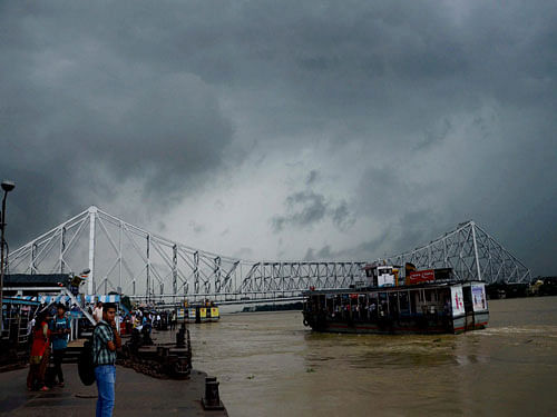 Peoples wait at a ferry ghat near the Howrah Railway station as dark clouds cover the sky in Kolkata on Thursday. PTI Photo