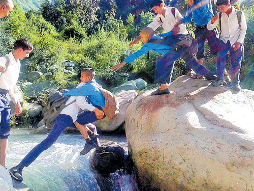 leap of faith: Students take risk to cross a river in the absence of a bridge at Badhul area of Rajouri on Tuesday. PTI