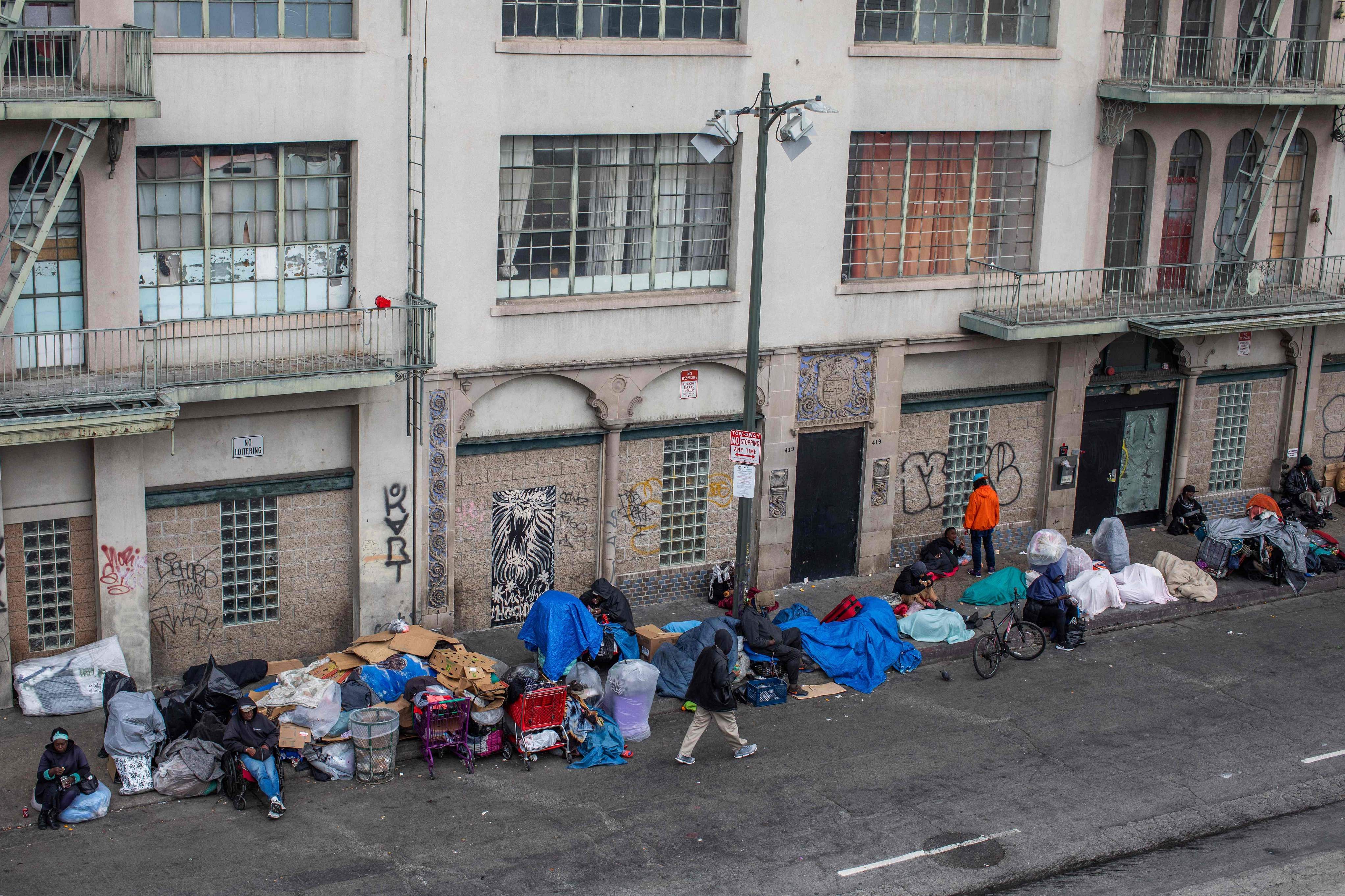 homeless people make shelters on the sidewalk in front of the Midnight Mission at Skid Row in downtown Los Angeles, California. (Credit: AFP)