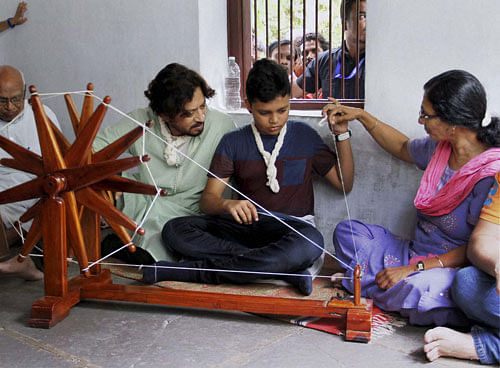 Actor Irfan Khan along with his son spinning cotton on a Charkha during a visit to Gandhi Ashram in Ahmedabad on Sunday. PTI Photo