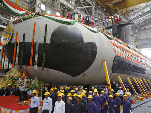 Employees stand in front of the Indian Navy's first Scorpene submarine before being undocked from Mazagon Docks Ltd, a naval vessel ship-building yard, in Mumbai April 6, 2015. REUTERS