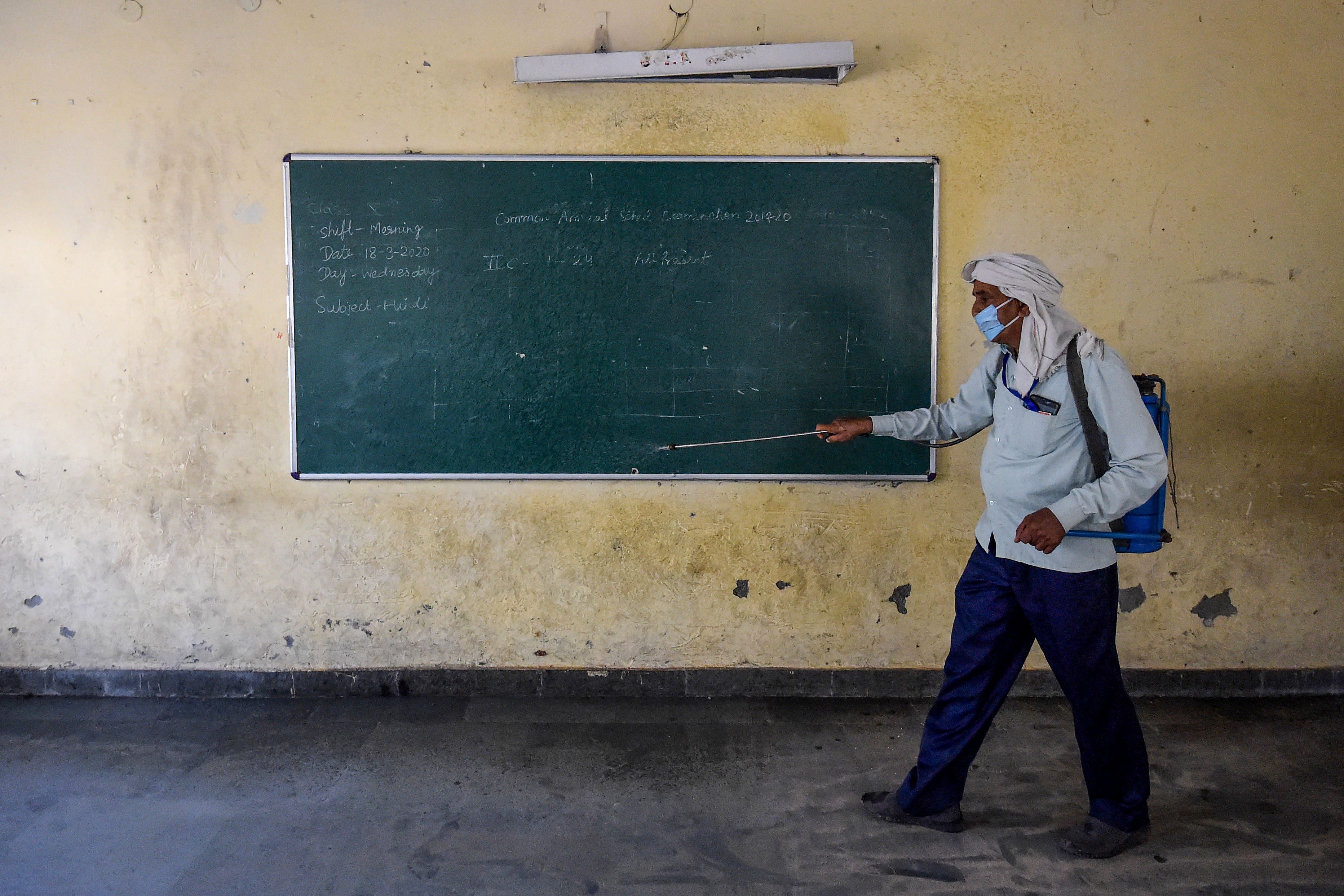  New Delhi: A worker disinfects a classroom of a government school where migrants are staying. (AFP)