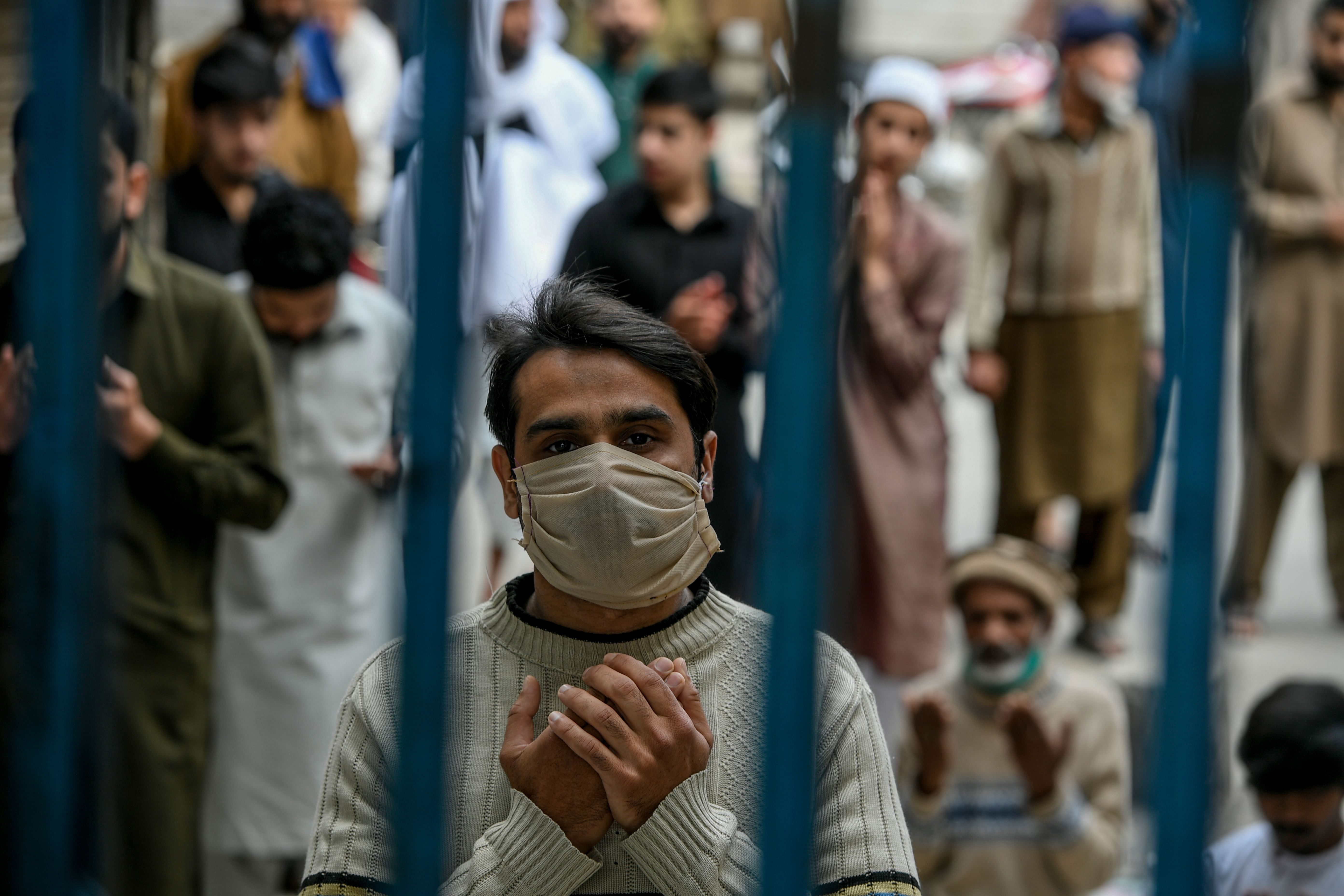 A Muslim worshipper wearing a facemask prays during Friday prayers outside the closed gate of Jamia Mosque during a government-imposed nationwide lockdown. (Credit: AFP)