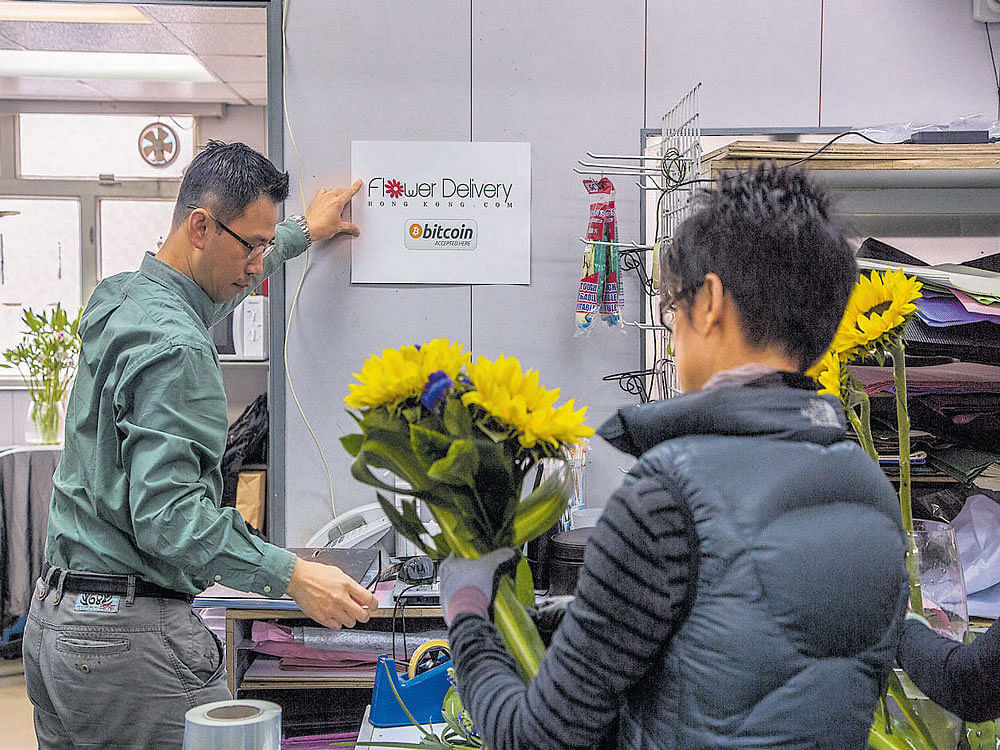 volatile state: A man puts up a poster announcing that his flower shop accepts bitcoins in Hong Kong. Some wealthy Chinese have used bitcoin to evade their government's strict controls on moving money in and out of the country, according to bitcoin specialists. nyt file photo
