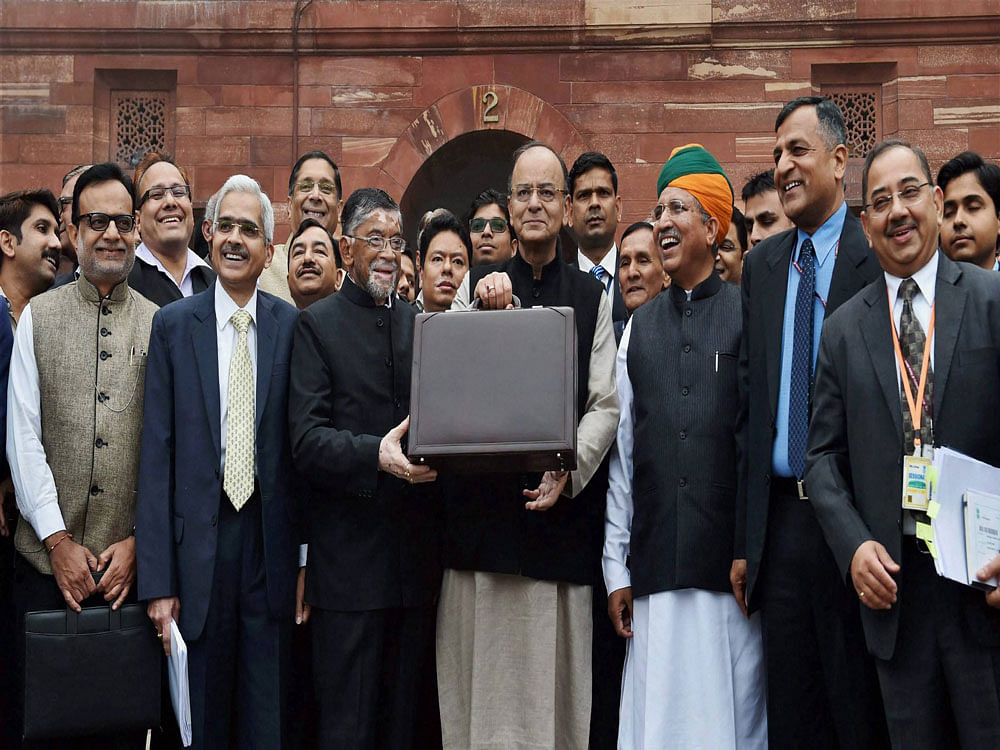Finance Minister Arun Jaitley (C) stands outside his office at North Block holding the briefcase containing the Union budget for 2017 and is flanked by MoS Arjun Meghwal (3rd R) and Santosh Gangwar (3rd L), on Wednesday,in New Delhi. PTI Photo