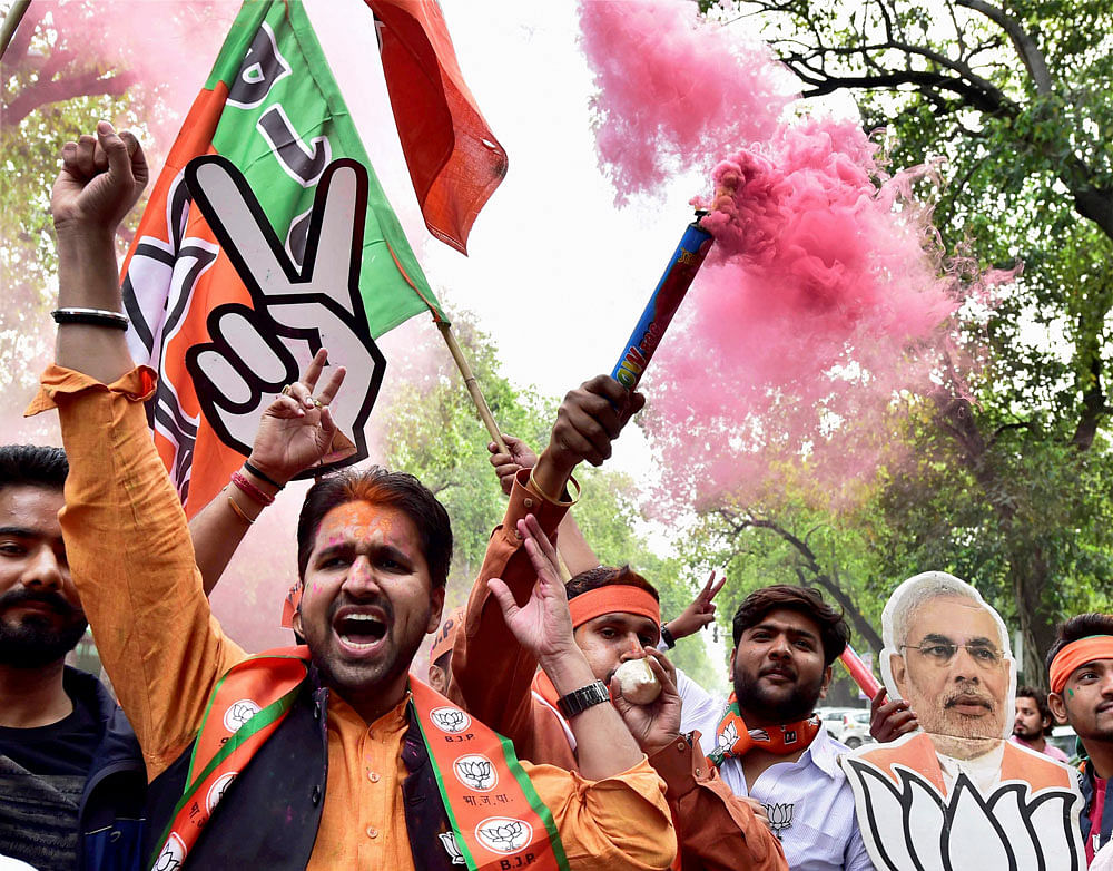 BJP supporters and workers celebrate the party's victory in the assembly elections with colours, at party headquarters in New Delhi on Saturday. PTI Photo