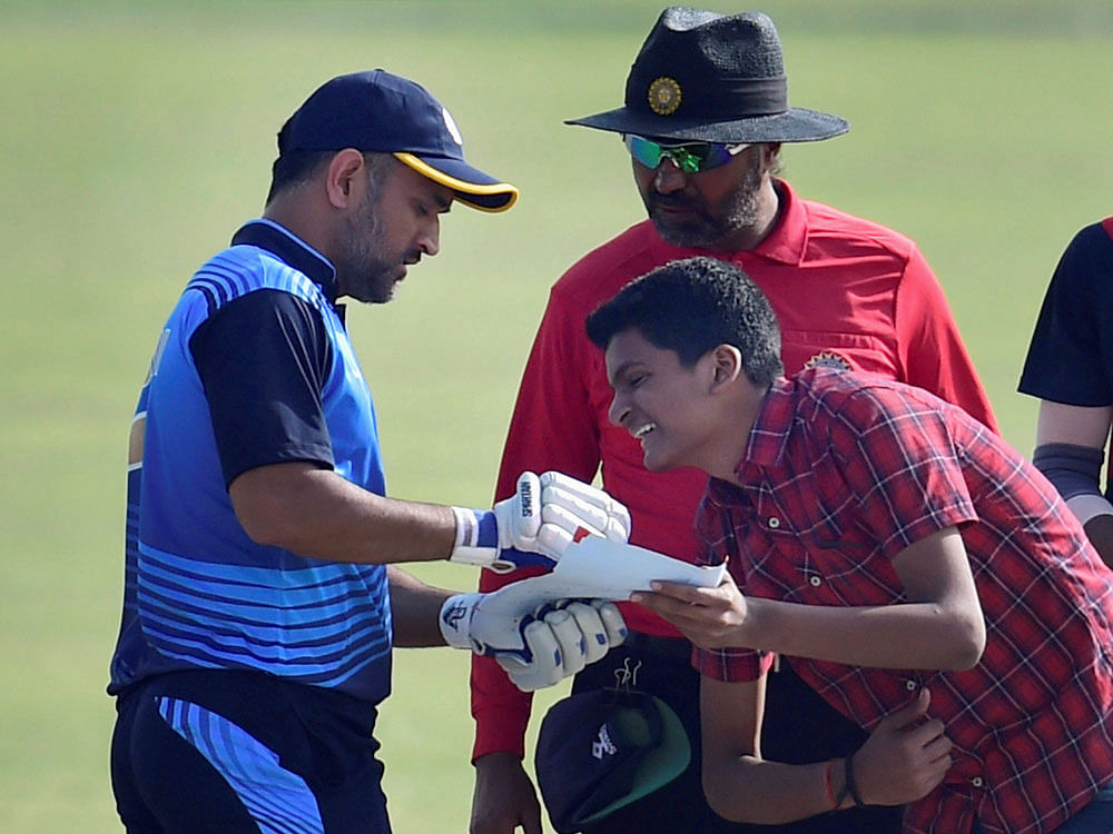 Jharkhand team captain M S Dhoni obliges a young fan during the Vijay Hazare trophy match against Viharbha in New Delhi on Wednesday. PTI Photo