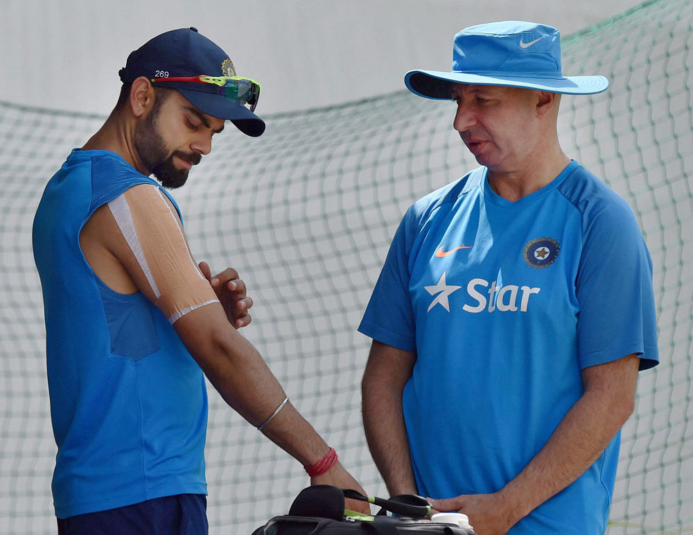 India's skipper Virat Kohli with team physiotherapist Patrick Farhart during a practice session at HPCA Stadium in Dharamsala on Thursday ahead of the final test match against Australia. PTI Photo