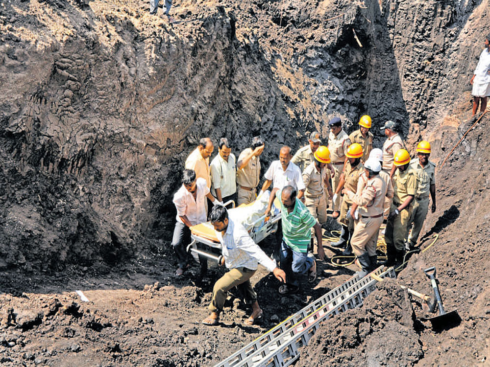 Workers bring out a body at Savadi, in Ron taluk of Gadag district, on Wednesday. DH photo