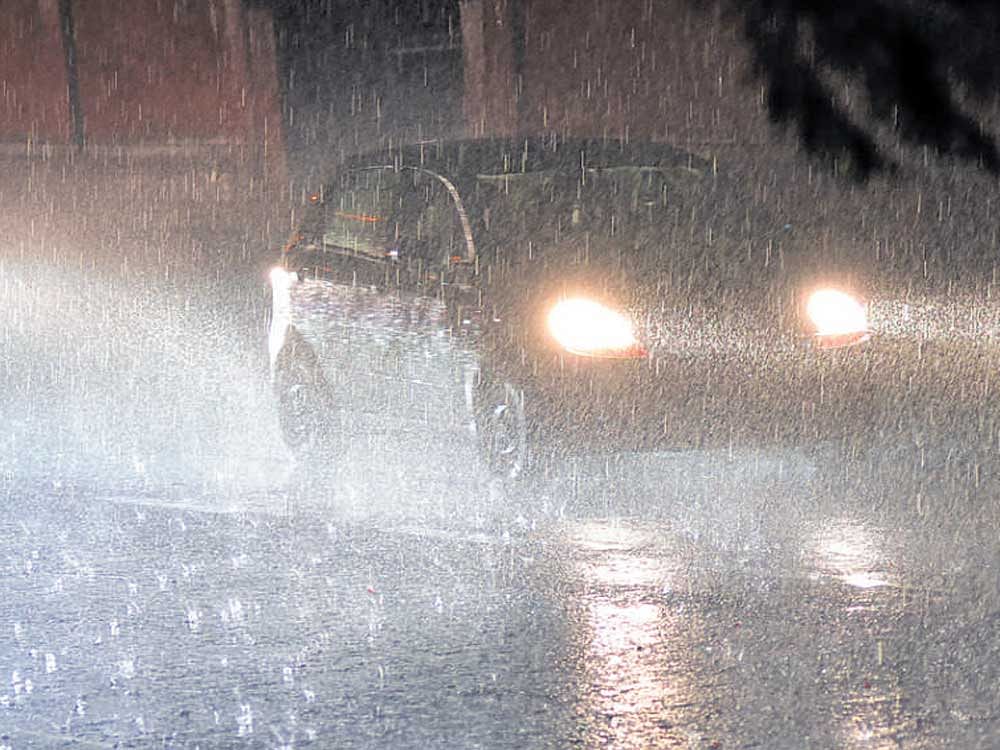 A car makes its way as it rains in Mysuru on Sunday. DH Photo