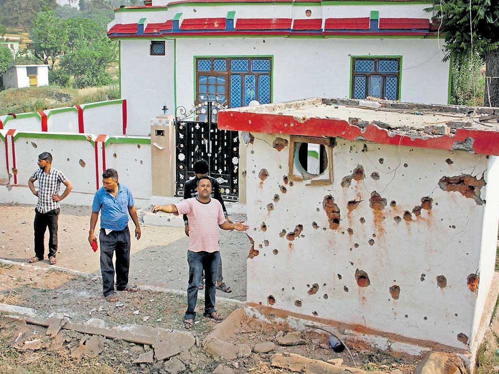 Villagers living near the border point at the damage caused to the wall of a house after mortar shelling from Pakistan, at Jhanghar village near the Line of Control at Nowshera sector in Jammu on Sunday. PTI