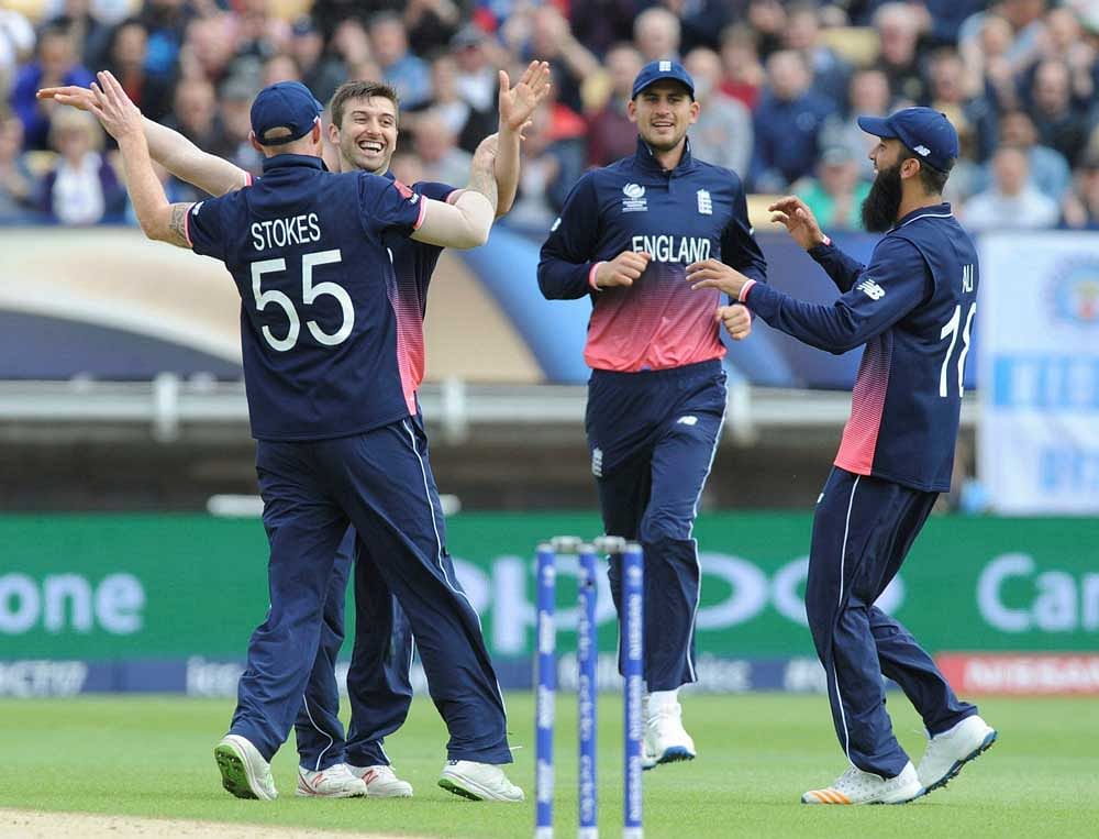 England's Mark Wood, 2nd left, celebrates with England's Ben Stokes, left, after bowling Australia's David Warner caught by England's Jos Buttler for 21 runs during the ICC Champions Trophy match between England and Australia at Edgbaston in Birmingham, England, Saturday, June 10, 2017.AP/PTI