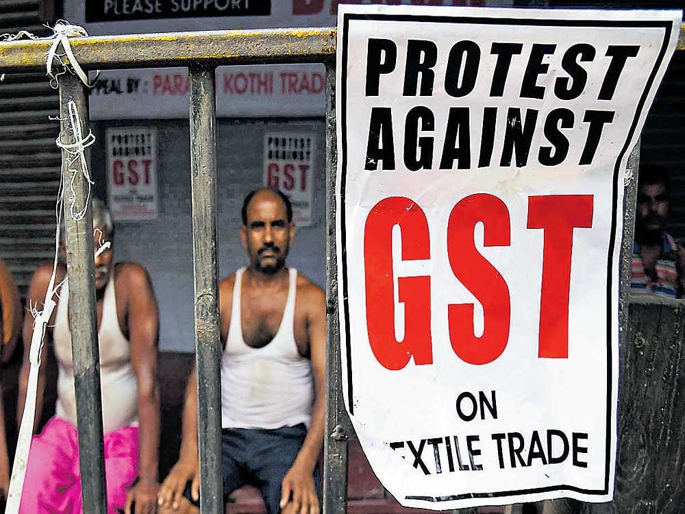 all is not well: Labourers look at posters against the GST in Kolkata on Wednesday. AFP