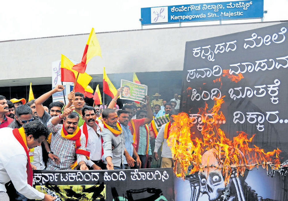 Members of Karnataka Rakshana Vedike burn a copy of a  signage with station names in Hindi near Kempegowda Metro station on Friday. DH&#8200;Photo