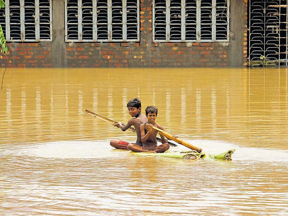 Boys row a makeshift raft at a flooded village in Howrah district, West Bengal on Wednesday. REUTERS