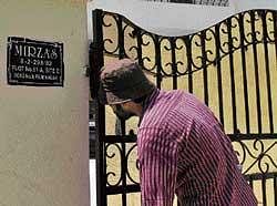 Looking  through: A journalist peeps through the gate of Sania Mirza in Hyderabad. Sania and Shoaib remained indoors on Thursday while family members went shopping. AFP