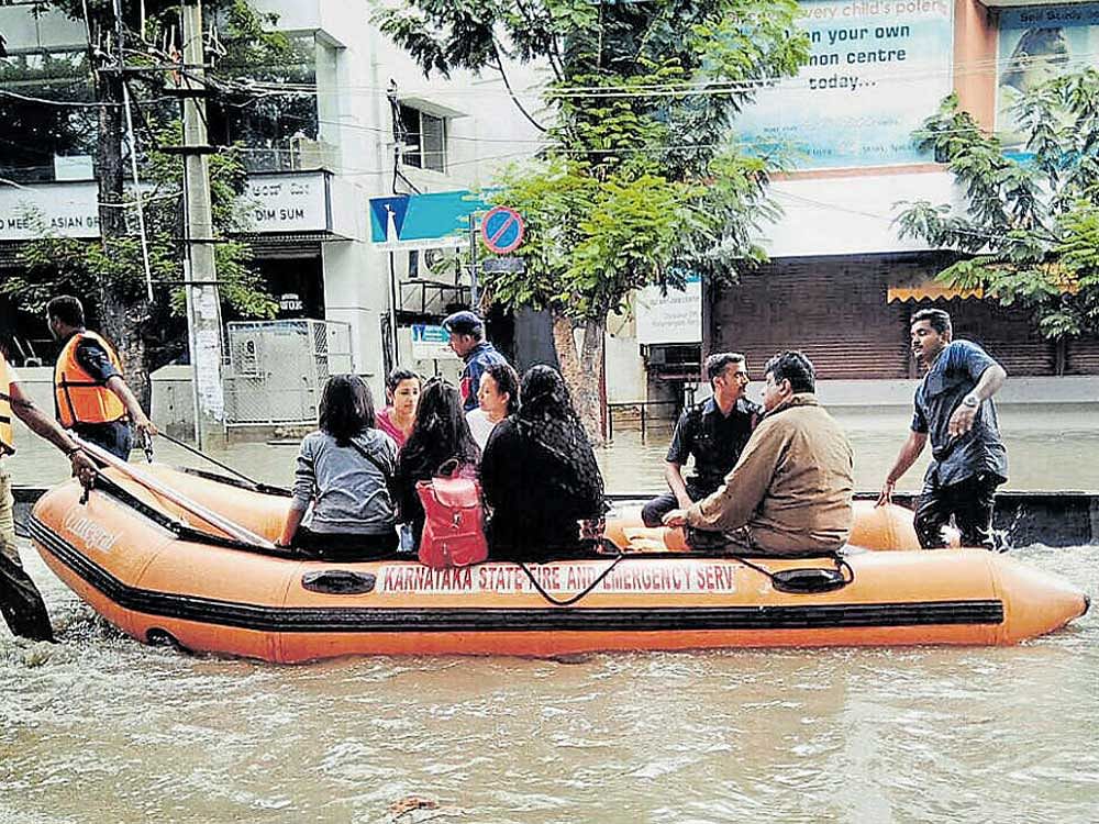 Firemen shift stranded people in a boat in Koramangala.