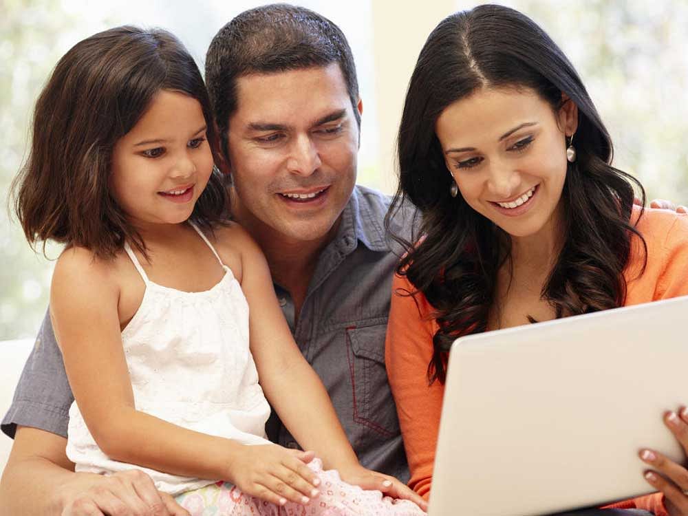 Hispanic family with laptop at home smiling
