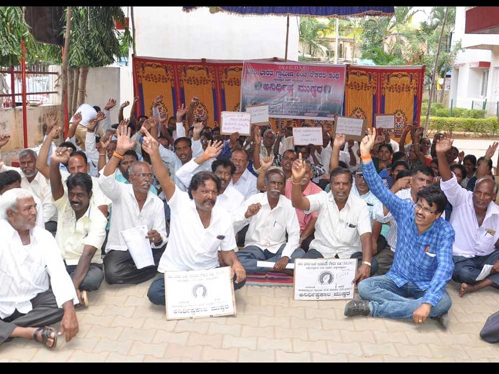 The office-bearers of rural postal employees association stage a dharna in front of the main post office in Chikkaballapur on Wednesday. dh photo