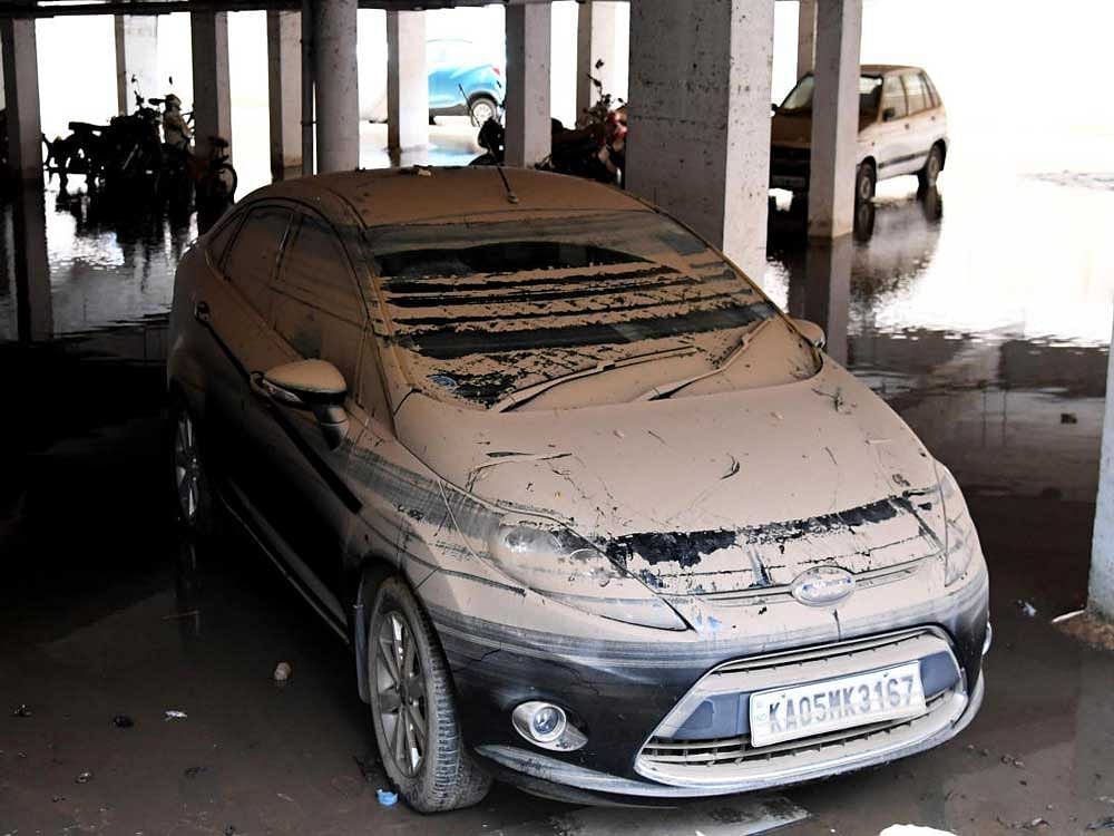 At Dollars Colony, J P Nagar, a car covered in sludge after Tuesday's deluge. Hundreds of vehicles parked in basements and low-lying areas are being towed away for repairs. DH PHOTO Kishor Kumar Bolar