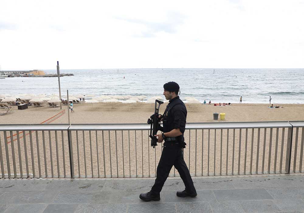 A heavily armed Catalan Mossos d'Esquadra officer patrols along La Barceloneta beach in Barcelona. Police has expanded the scope of the manhunt to capture a Moroccan national suspected to be one of the perps and to identify the network responsible for the attacks. Reuters photo.