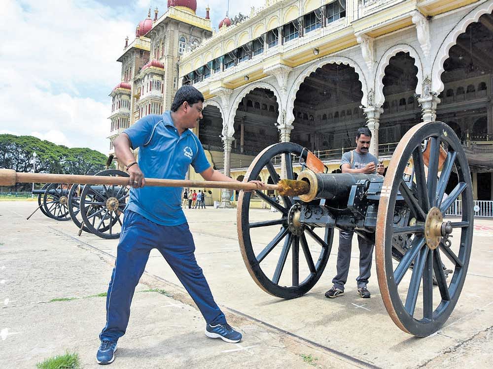 Police personnel clean a cannon at the Mysuru Palace in Mysuru on Saturday. DH photo