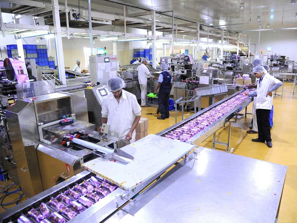 Workers watch over a batch of cookie packs at the packaging unit of the Unibic factory in Bengaluru. DH Photo by Srikantha sharma r