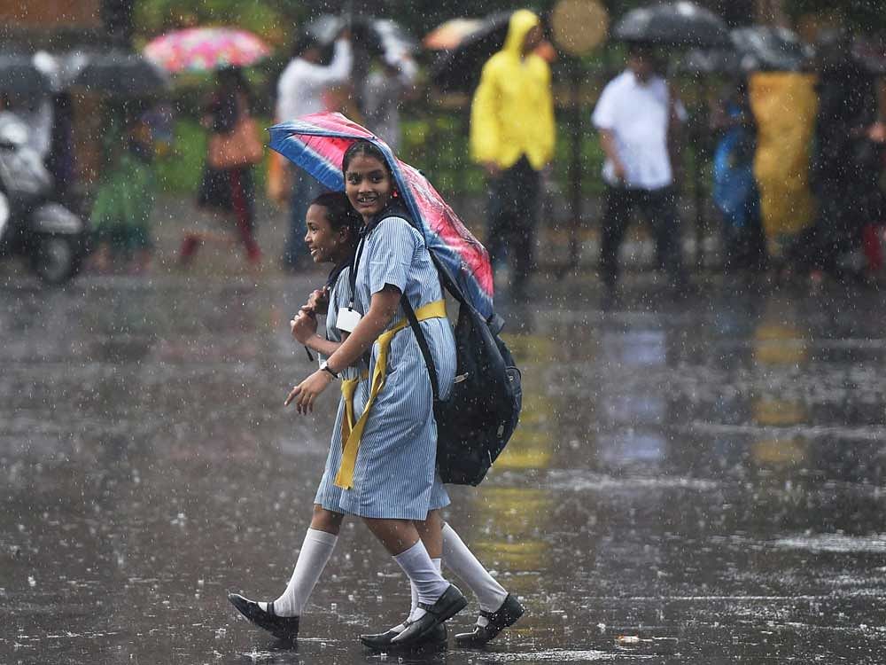 School children holding an umbrella during the rains in Mumbai on Monday. PTI Photo