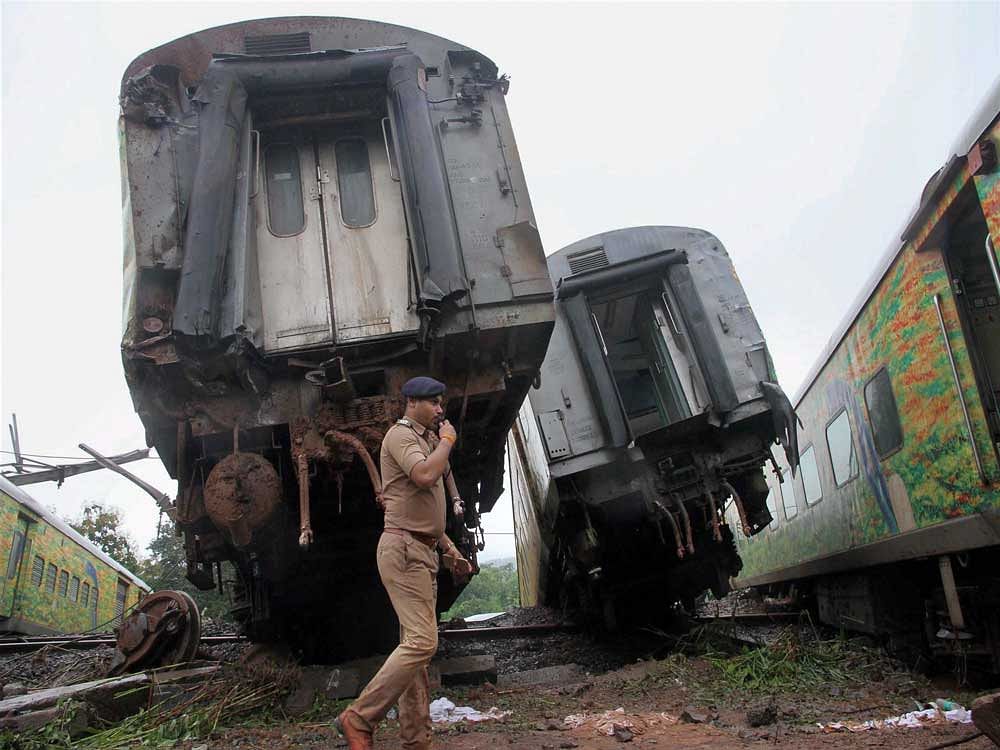 A policeman walks near the derailed coaches of Nagpur-Mumbai Duronto Express train near Asangaon in Maharashtra's Thane district on Tuesday morning. No casualties or injuries were reported, officials said. PTI Photo