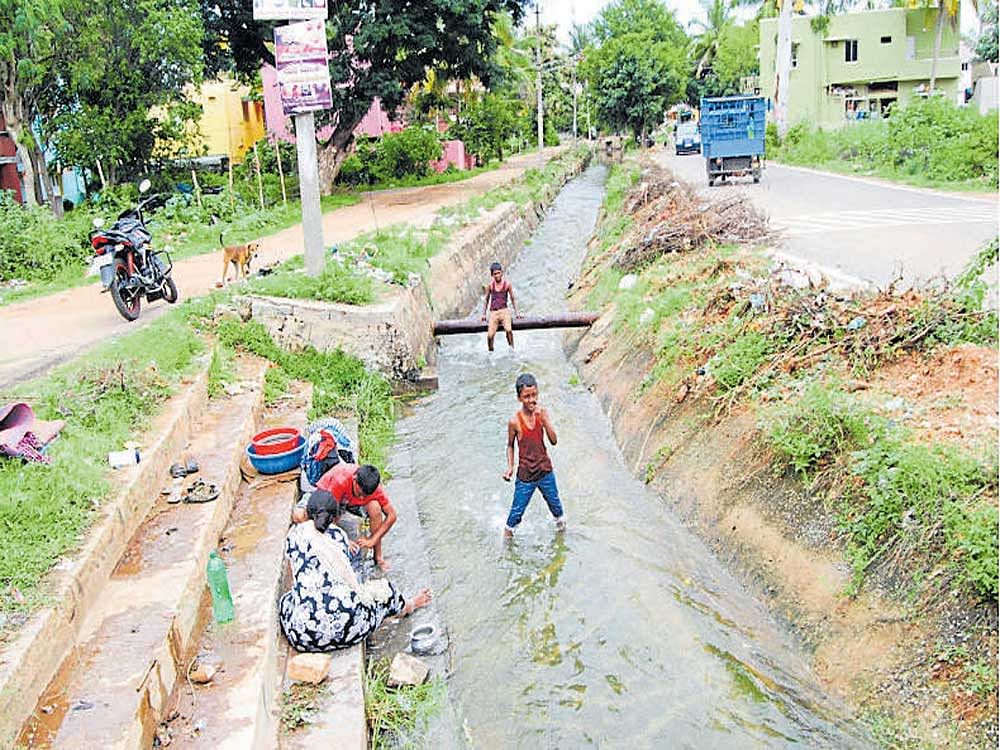 Women wash clothes while children play in the sub-canal of the Visvesvaraya Canal in Mandya.