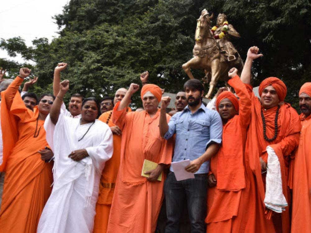 Seers of various Lingayat mutts and Kannada actor Chethan stage a demonstration in front of the Basaveshwara statue at Chalukya Circele in Bengaluru on Wednesday, seeking  religious minority tag for Lingayats. DH