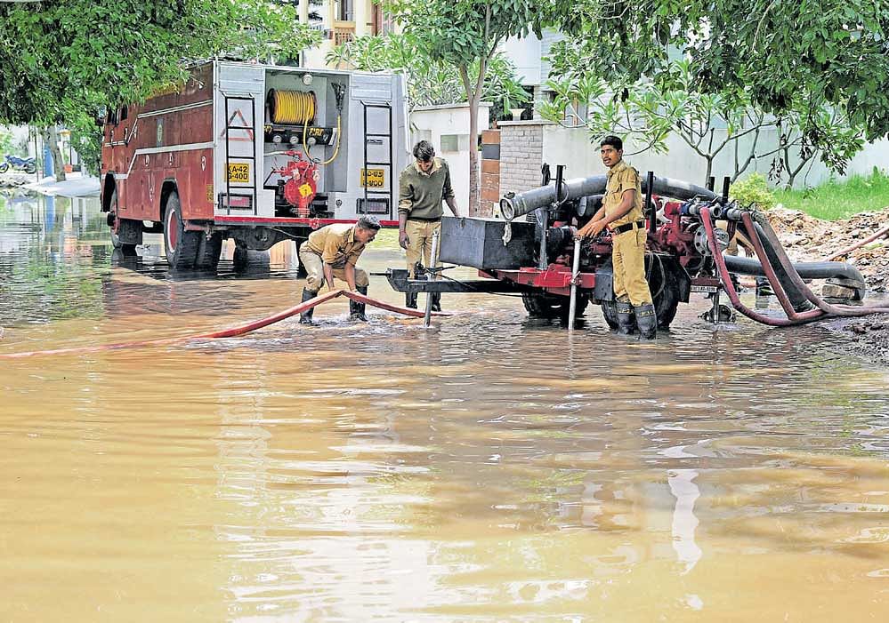 Fire and Emergency Services personnel pump out rainwater from a flooded basement in HSR Layout, 6th Sector, on Sunday. DH photo