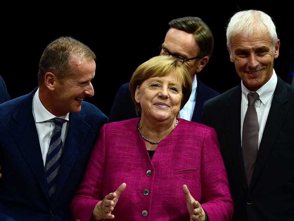 German Chancellor Angela Merkel (C) is flanked by Volkswagen chairman Matthias Mueller (R) and board  member Herbert Diess (2nd L) as she visits the company's booth at the auto show in Frankfurt. AFP