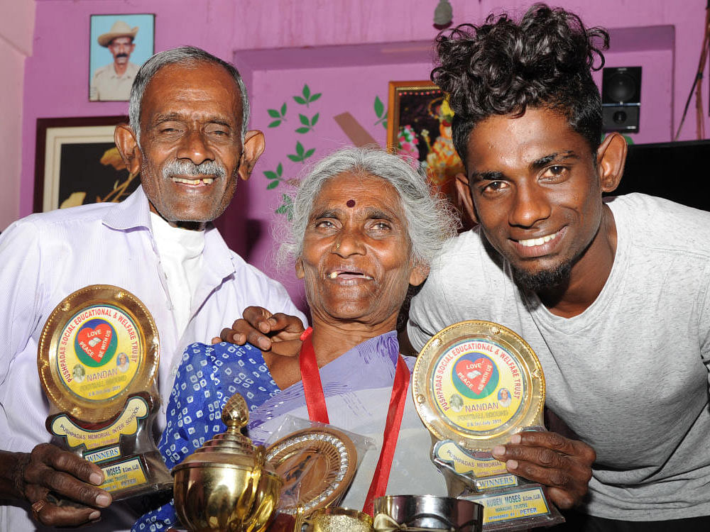 Grandparents of Hendry Antonay Krishna Murthy, Dharmavati and brother Ajay Alex happly showing Hendry's trophy at their residence in Bengaluru on Friday. Hendry has been selected in the Indian team for the FIFA U-17 World Cup. DH Photo by Srikanta Sharma R