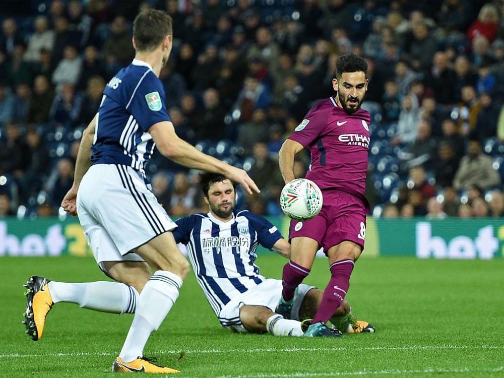 West Bromwich Albion's Argentinian midfielder Claudio Yacob (C) is booked for this tackle on Manchester City's German midfielder Ilkay Gundogan (R) during the English League Cup third round football match between West Bromwich Albion and Manchester City at The Hawthorns in West Bromwich, central England. AFP PHOTO