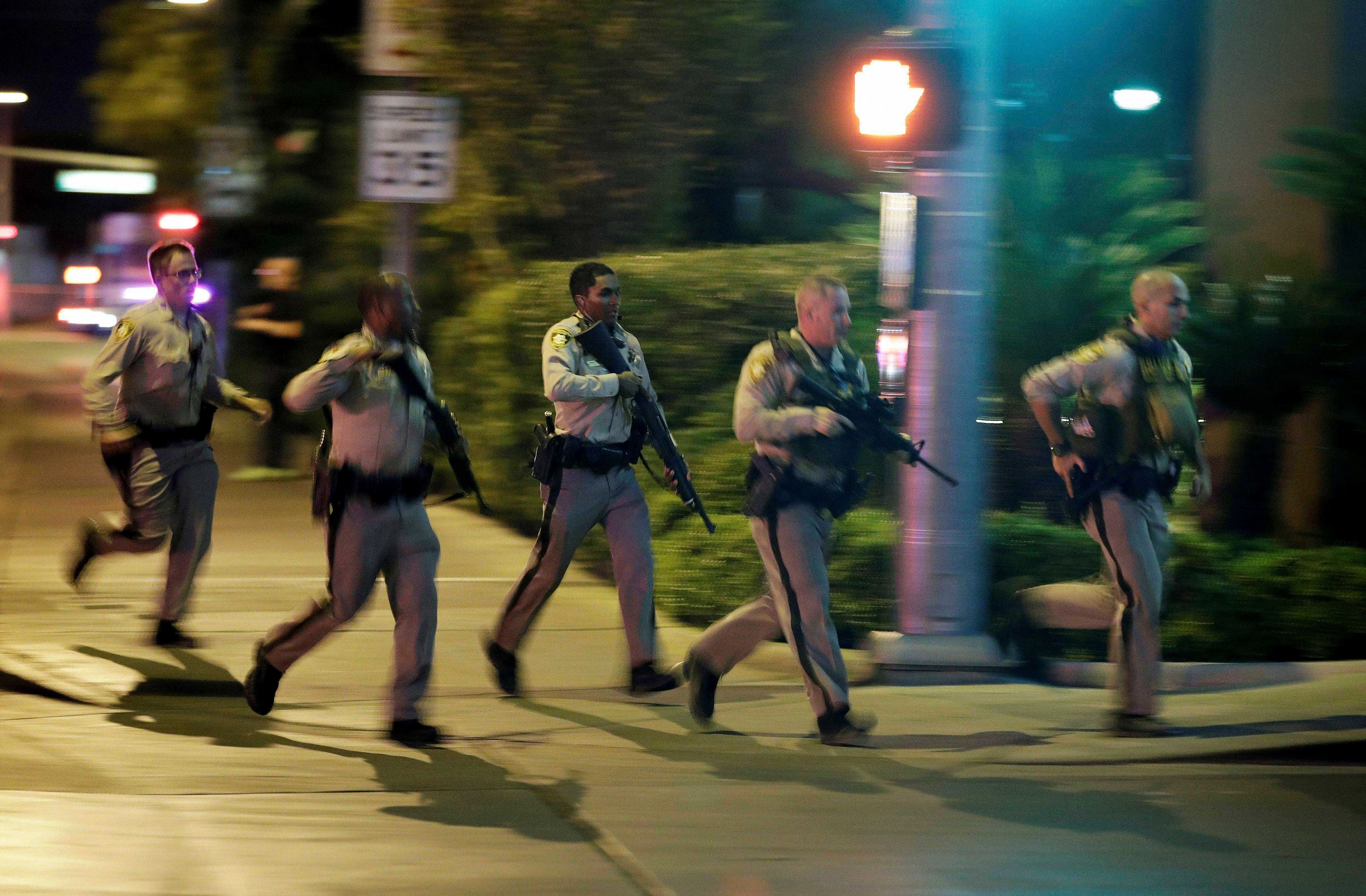 Police run to cover at the scene of a shooting near the Mandalay Bay resort and casino on the Las Vegas Strip, Sunday, Oct. 1, 2017, in Las Vegas. Multiple victims were being transported to hospitals after a shooting late Sunday at a music festival on the Las Vegas Strip. AP/PTI